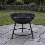 Cast iron fire bowl with grill grate in a black stand on granite setts