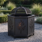 Hexagonal black steel fire pit with leaf cut-outs and mesh spark guard on gravel
