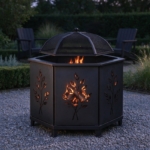 Hexagonal fire pit glowing through its leaf cut-outs at dusk